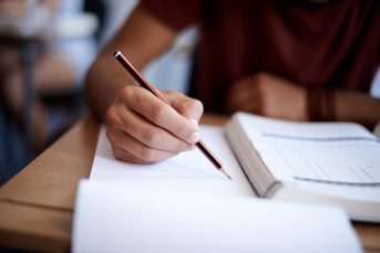 Closeup shot of a young man writing on a note pad